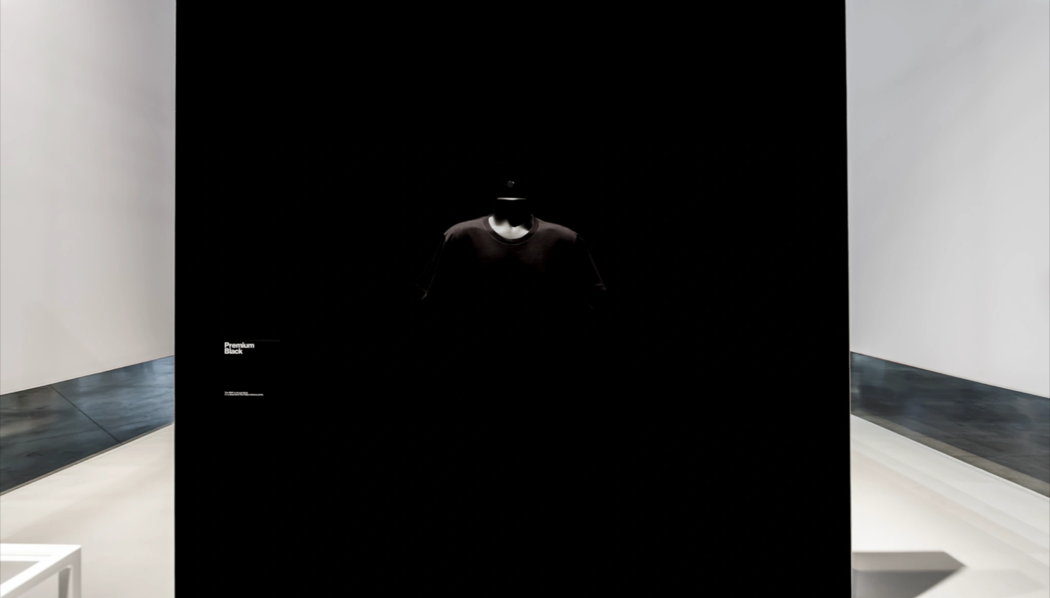 American Apparel campaign image showing a black T-shirt on a dark display in a gallery-like setting.