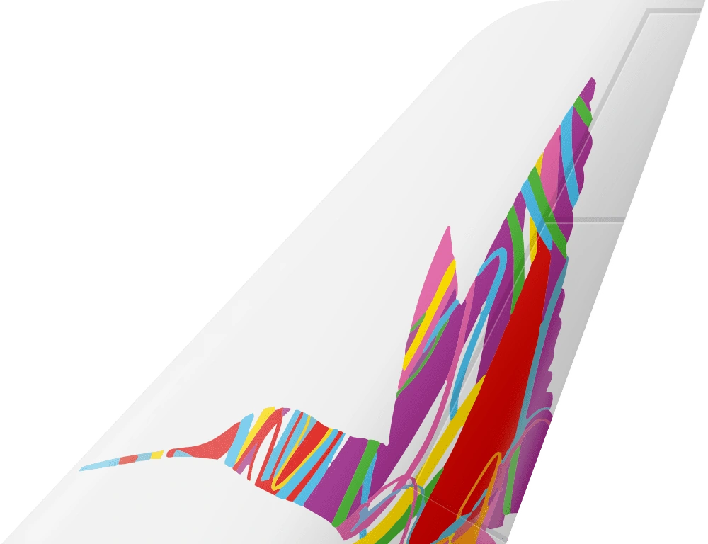 Close-up of a white aircraft tail with the Caribbean Airlines hummingbird formed from bright, flowing coloured lines.
