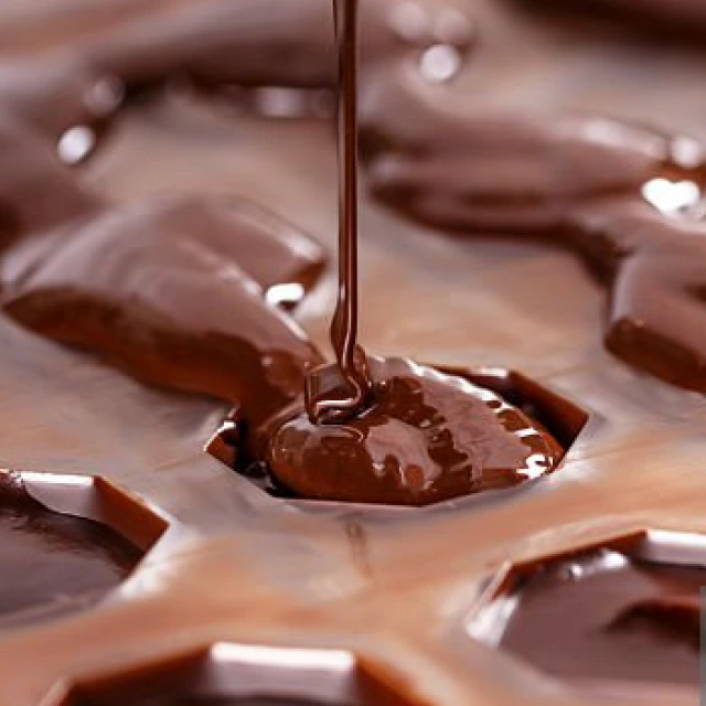 Chocolate being poured into a mould at close range, showing the glossy texture and the making process.