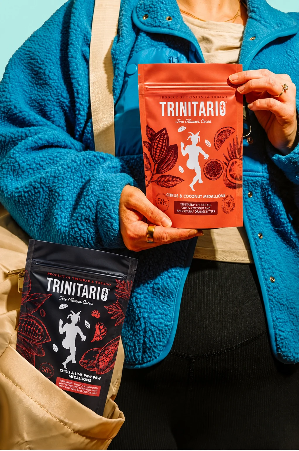 Citrus and Coconut and Chilli and Lime Paw Paw pouches held against a turquoise jacket.