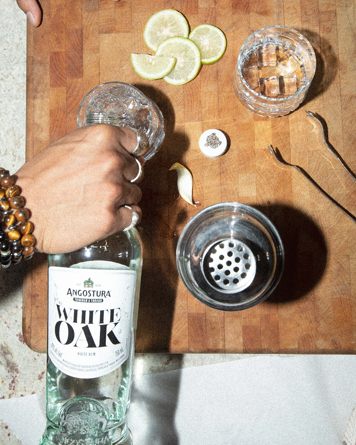 White Oak rum with its evolved label, alongside limes, glasses and a cocktail shaker