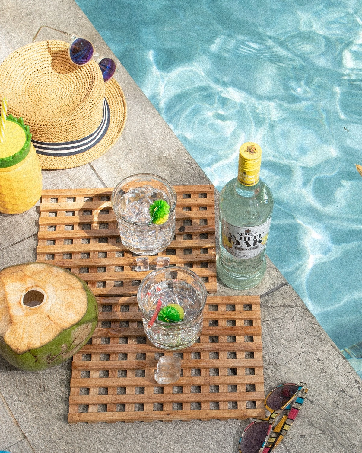 White Oak coconut rum beside a swimming pool with coconut, drinks and a sun hat.
