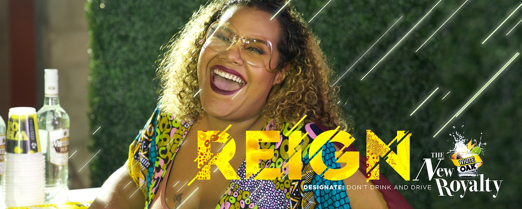 Reign outdoor artwork featuring a smiling woman in a colourful outfit against a green wall.